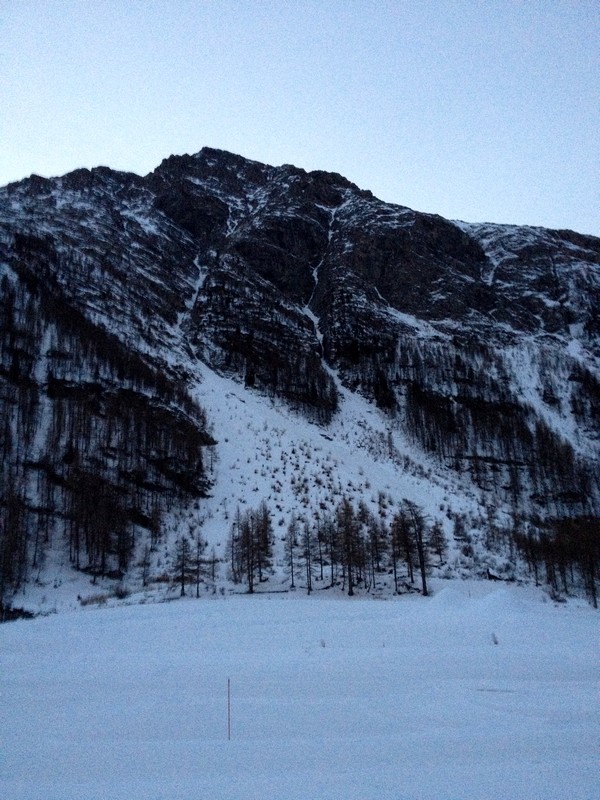 La voie débute en haut du cône de neige de droite.